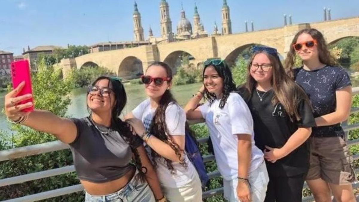 Unas jóvenes se hacen un selfie con el Pilar de fondo.