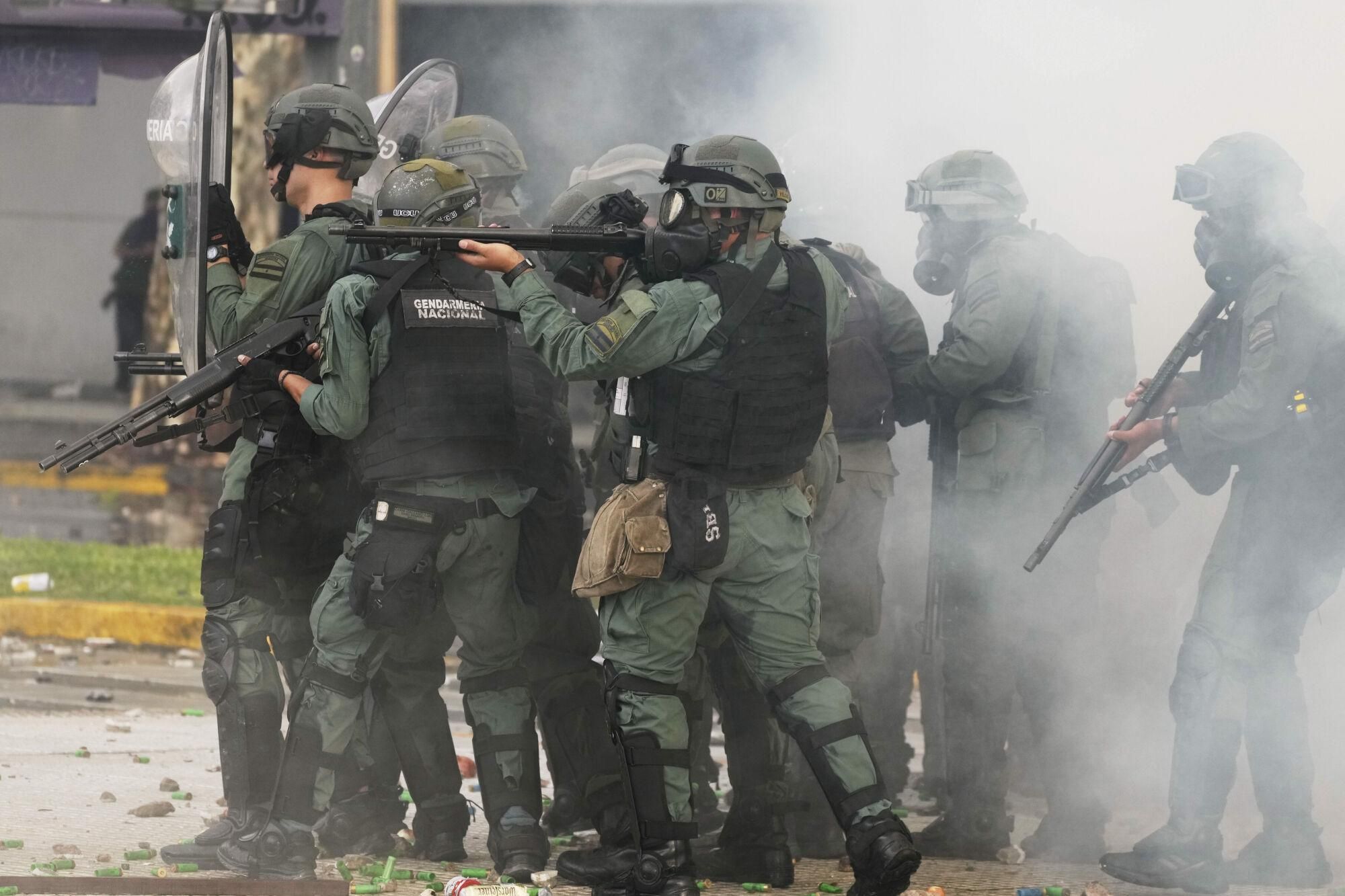 Police hold up their guns during clashes against soccer fans who joined retirees protesting for higher pensions and against austerity measures implemented by Javier Milei's government in Buenos Aires, Argentina, Wednesday, March 12, 2025. (AP Photo/Natacha Pisarenko). EDITORIAL USE ONLY/ONLY ITALY AND SPAIN