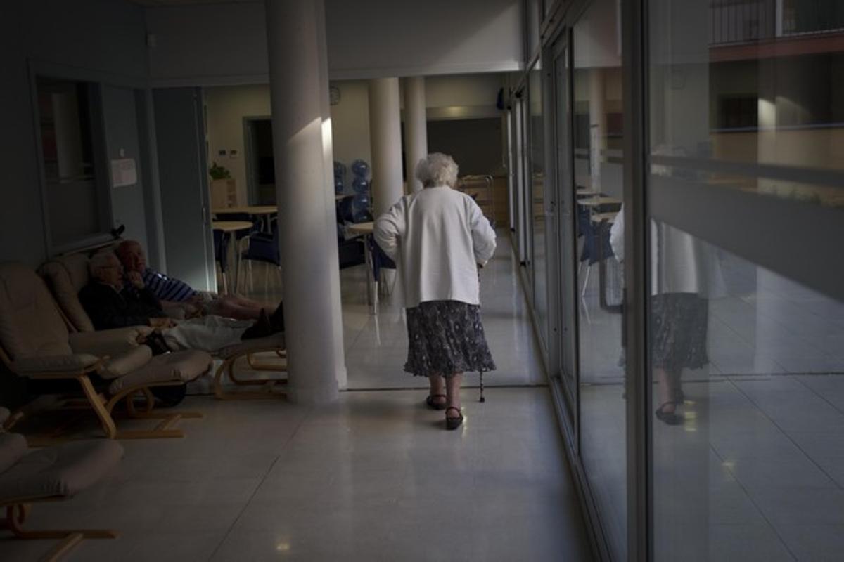  Una anciana camina en soledad por los pasillos de una residencia.