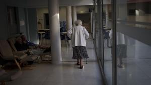 Una mujer pasea en soledad por los pasillos de una residencia.