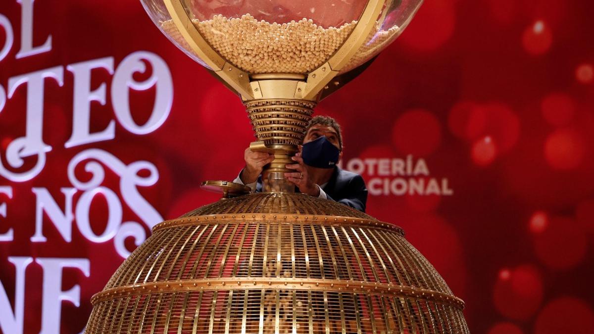 Persona depositando las bolas de la Lotería de Navidad en el bombo.