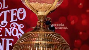 Persona depositando las bolas de la Lotería de Navidad en el bombo.