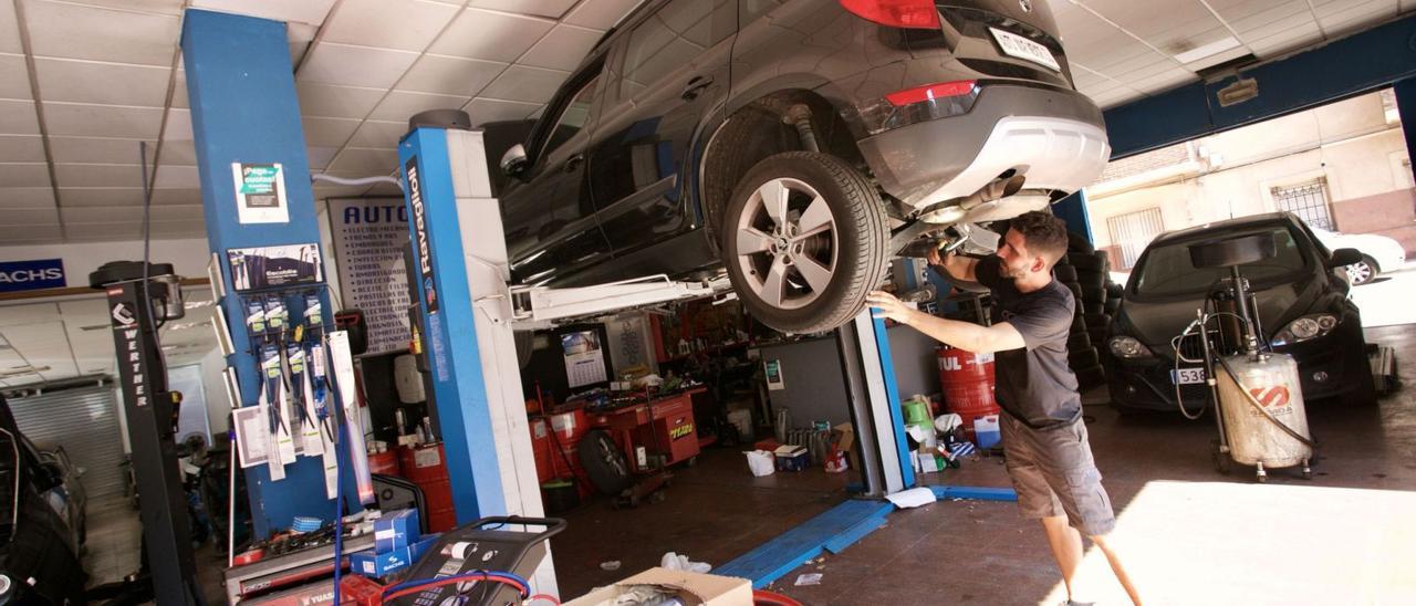 Un mecánico trabaja en lareparación de un coche en un taller.