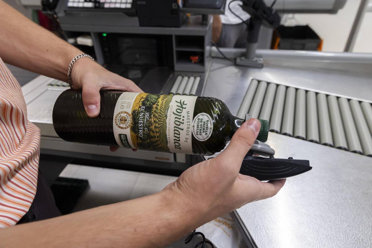 Una empleada quita un sistema de seguridad a una botella de aceite