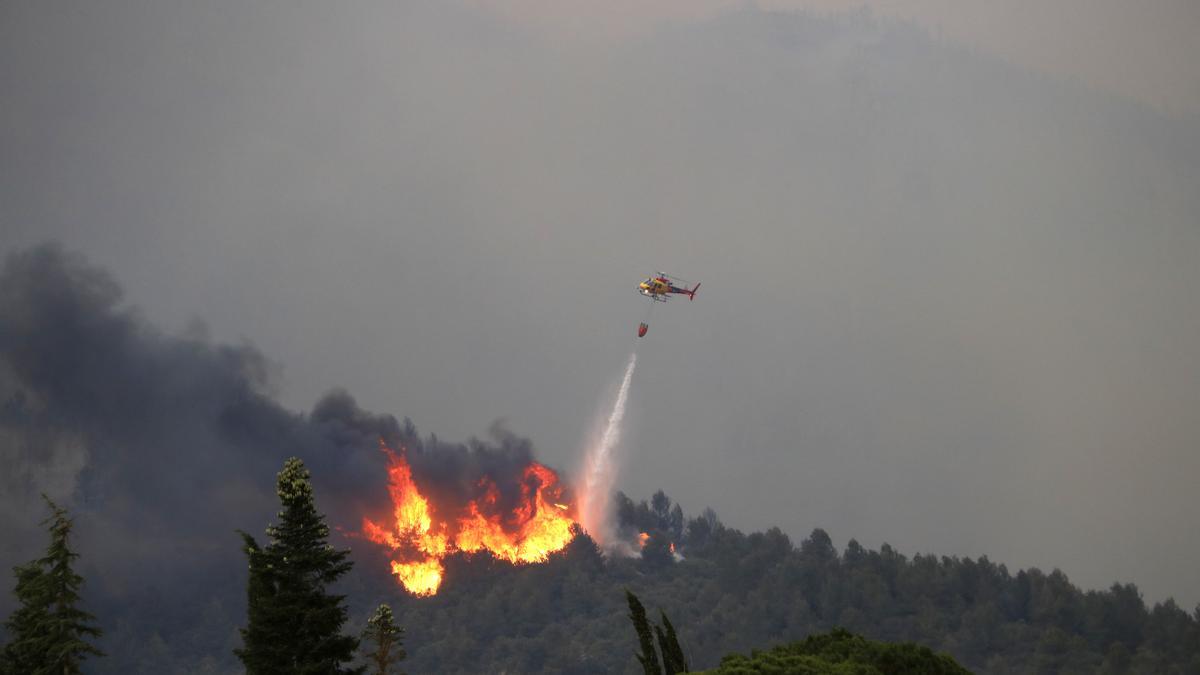 Un helicòpter llençant aigua a les flames de l&#039;incendi de Baldomar