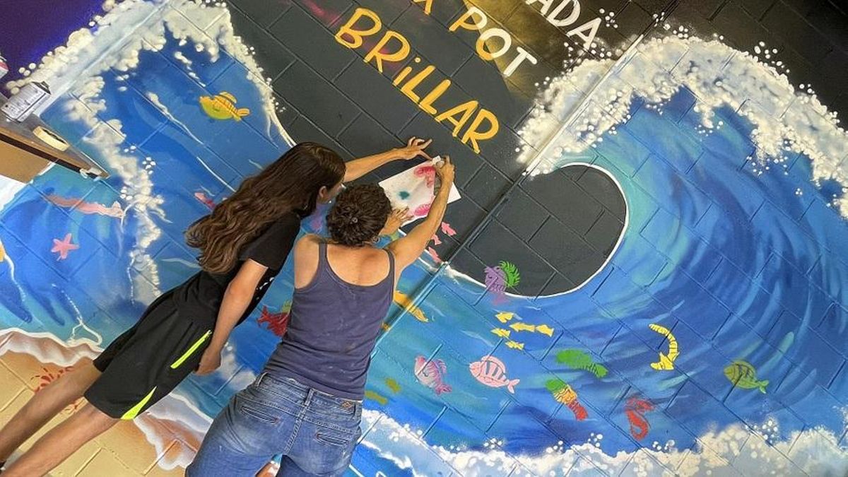 Joves pintant el mural.