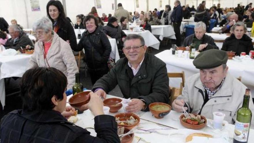 Asistentes a la fiesta degustan caldo y cazuelas con oreja, chorizo, lacón, patatas y grelos bajo la carpa instalada en Os Areais. // Noé Parga