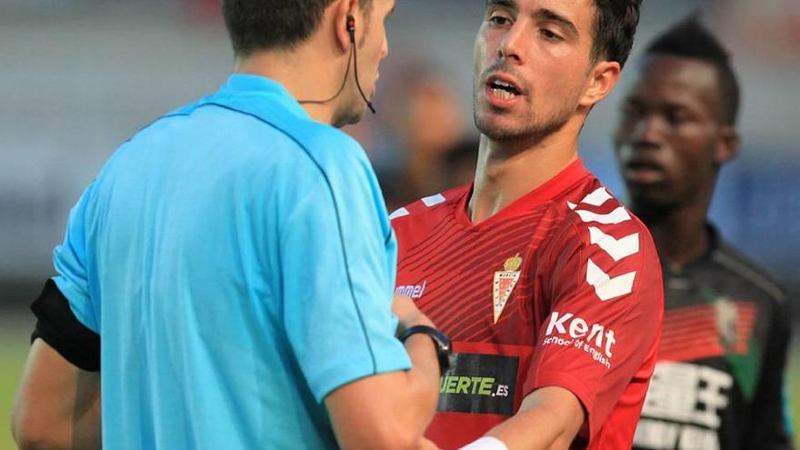 Pumar, el único lateral zurdo en el Murcia, habla con el árbitro.