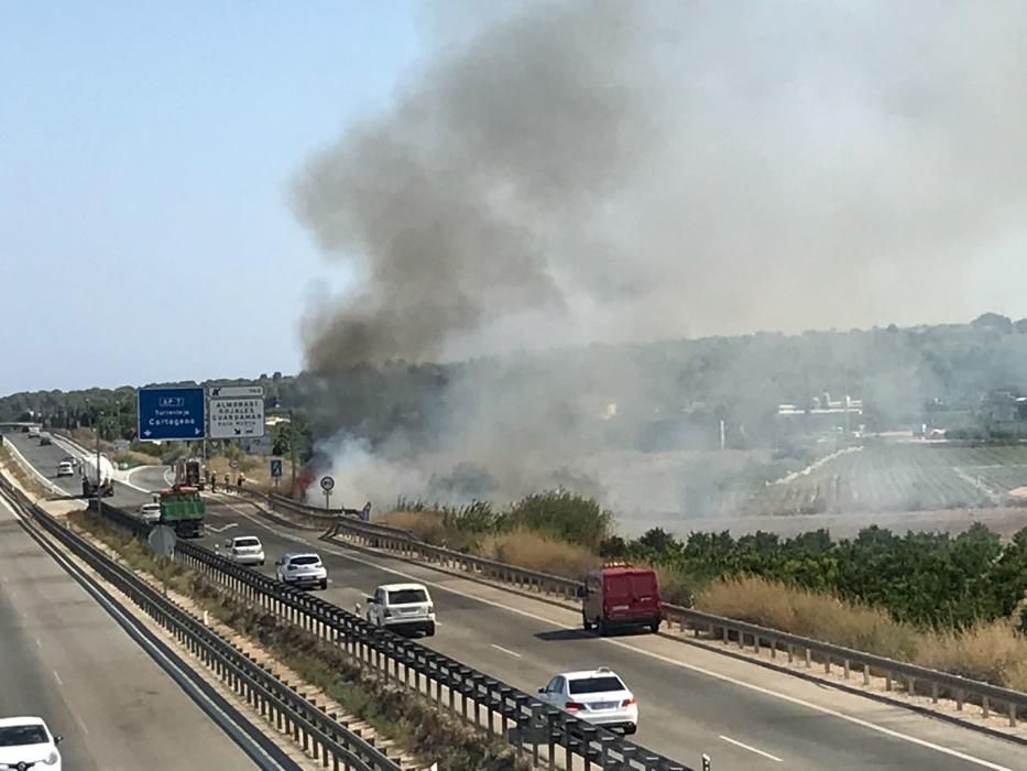 Los bomberos extinguen un incendio de matorral junto a la AP-7