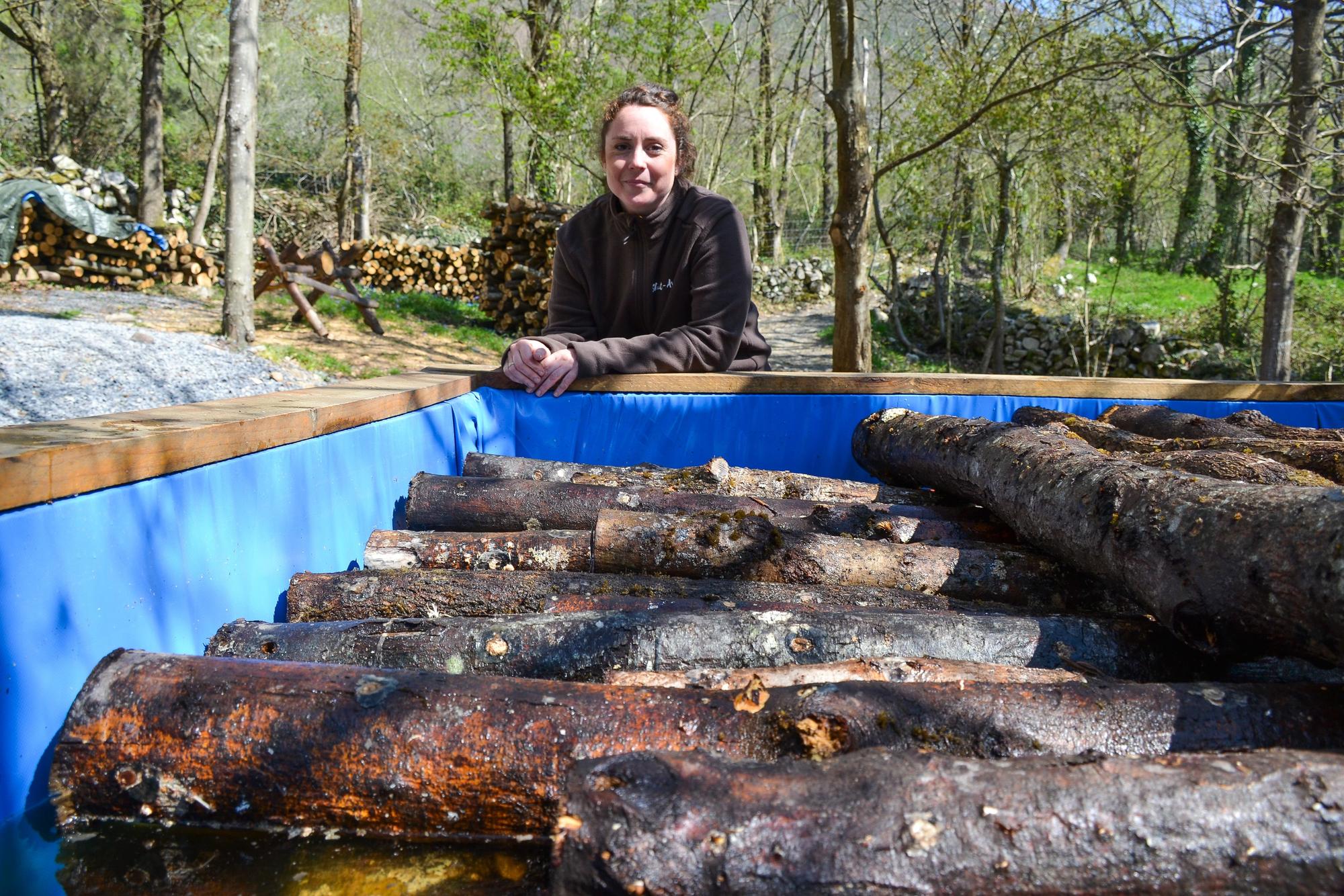 María Dolores Monge ante los troncos que están sumergidos en el agua, en el bosque de la finca que trabaja en Pando.