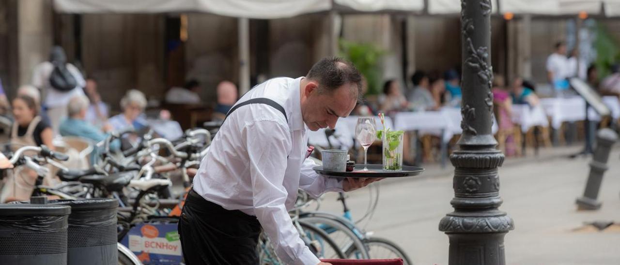 Un camarero limpia una mesa en una terraza.