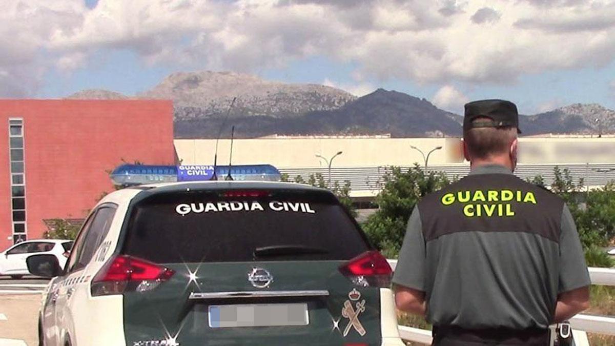 Un vehículo de la Guardia Civil y un agente de espaldas.