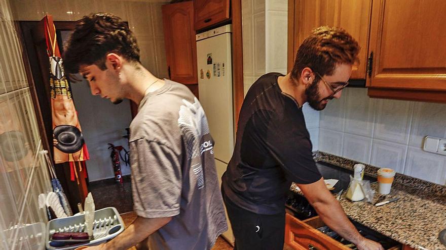 Dos jóvenes que comparten piso preparan la comida.