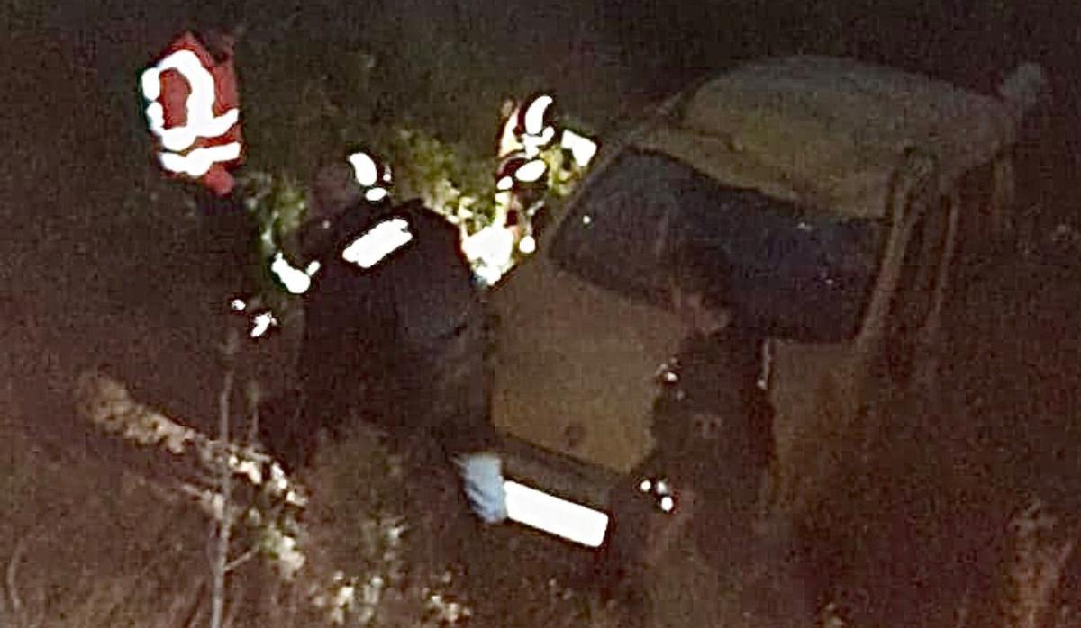 Los bomberos, junto al vehículo accidentado.