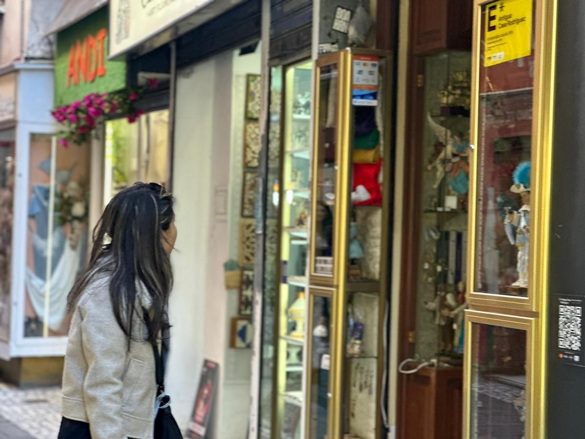 Una turista mira el escaparate de la Antigua Casa Rodríguez, en la calle Alcaicería de la Loza.