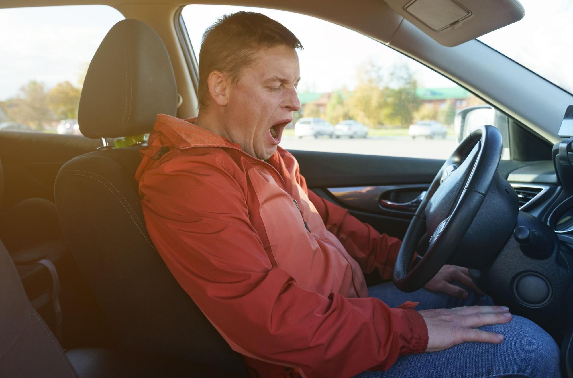 Tired driver man wants to sleep, yawns, opens his mouth. security concept.