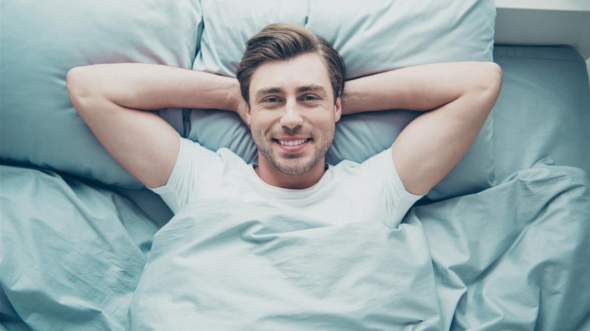 ONBARCELONA FOTO 123RF Top high angle photo of lovely blonde-haired person lying bed smiling  wearing white t-shirt indoors in room