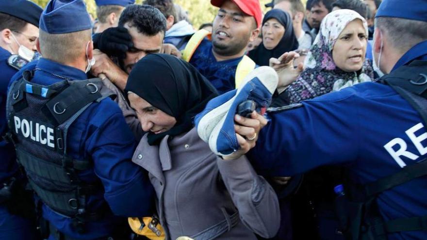 Refugiados forcejean con la policía húngara en Röszke.