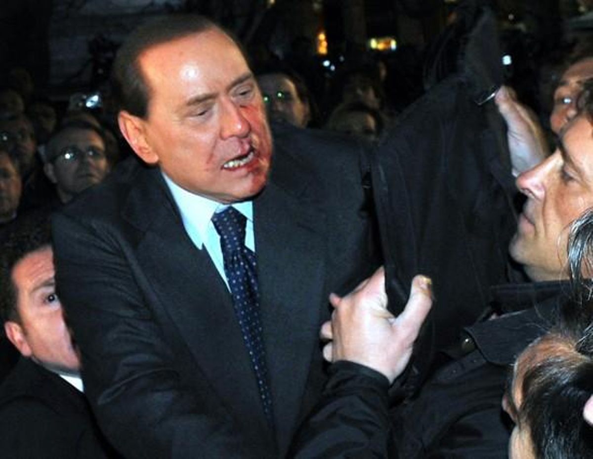 Silvio Berlusconi és auxiliat per la policia després de rebre a la cara l’impacte d’un objecte llançat per un disminuït psíquic, el desembre del 2009 a Milà.