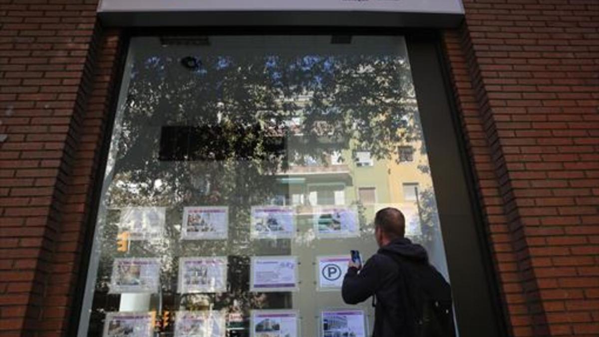 Un joven toma nota de una de las ofertas de pisos disponibles en alquiler en una agencia de Barcelona, esta semana.