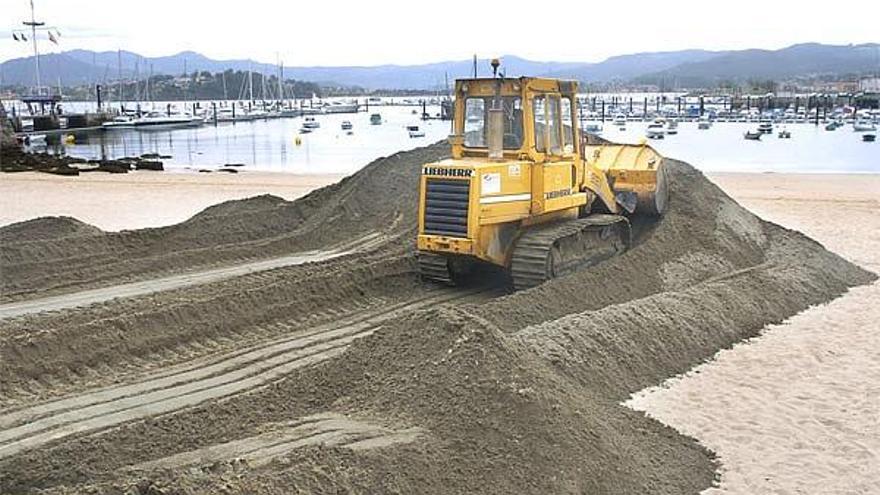 Una pala excavadora extendía ayer la arena en la playa de Ribeira.