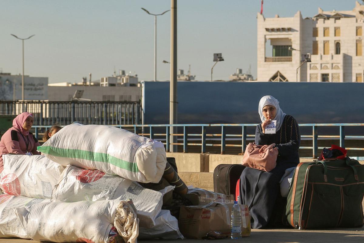 Una refugiada siria se sienta sobre sus pertenencias mientras espera con su familia para partir de Beirut de regreso a casa.