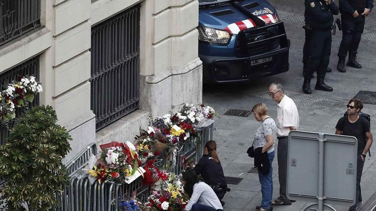 Varias personas depositan flores en la entrada de la Jefatura de la Policía Nacional en la Via Laietana.