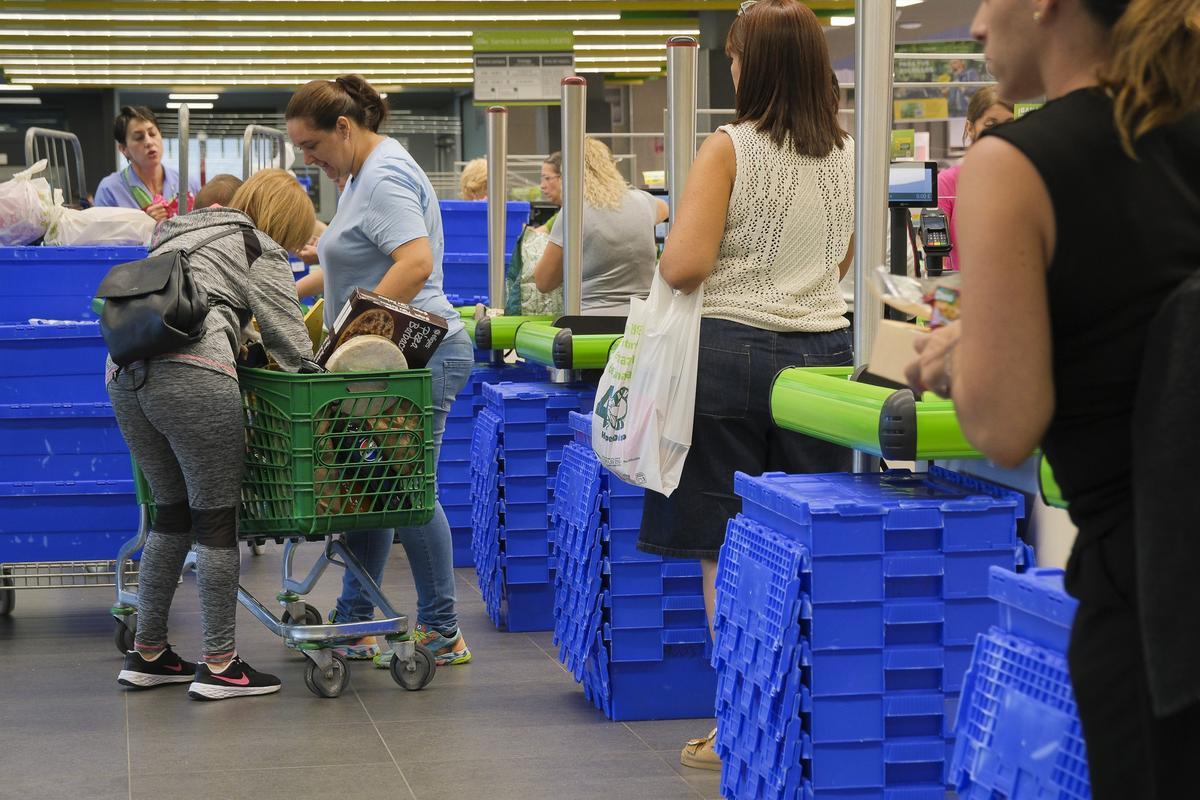 Dos mujeres depositan su compra en el carrito de un supermercado.