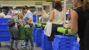 Dos mujeres depositan su compra en el carrito de un supermercado.
