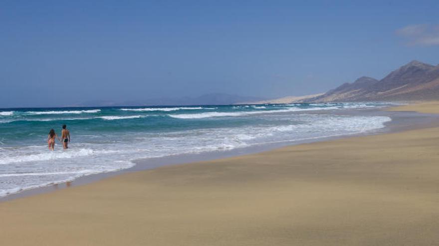 Una pareja se adentra en la paradisiaca playa de Cofete, en el sur de la Isla majorera.