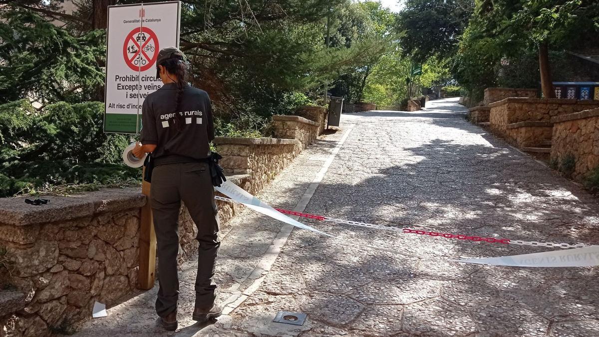 Una agent rural col·locant una cinta en un dels accessos al parc natural de Montserrat | ROGER JUNYENT