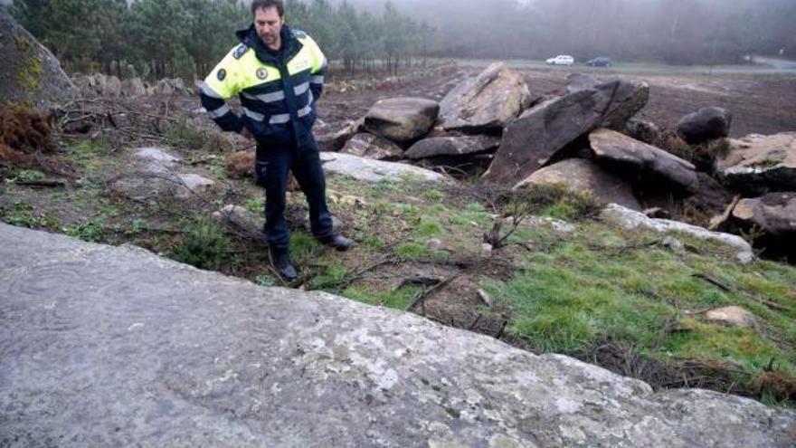 El Policía Local de Agolada posa entre los petroglifos y las piedras movidas de la finca.  // Bernabé/Javier Lalín