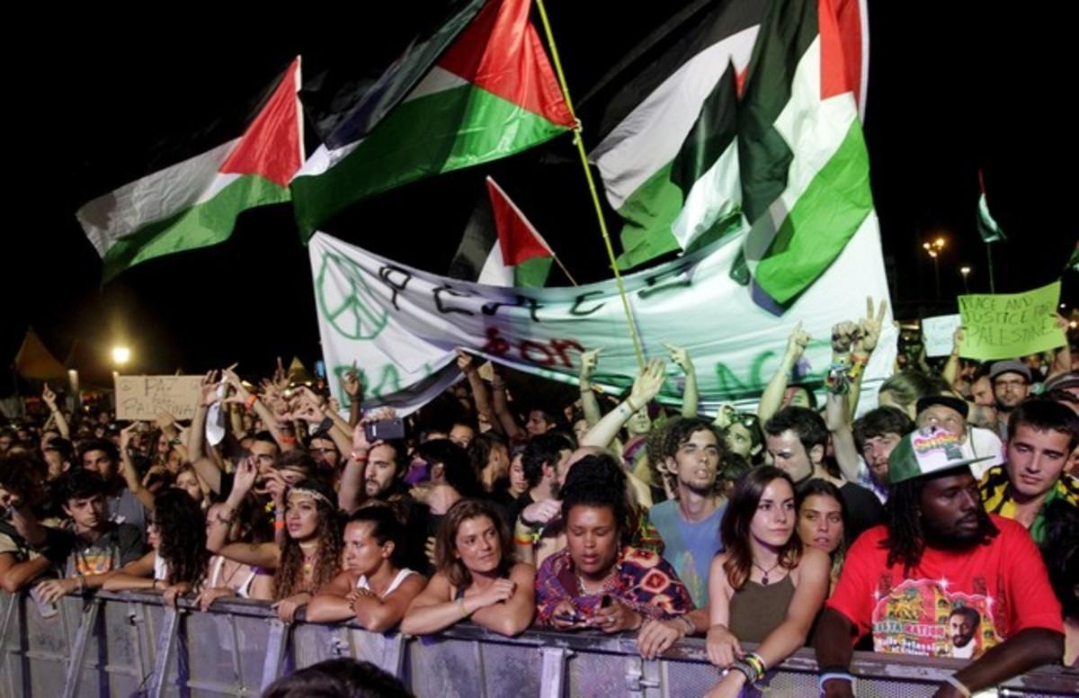 Palestinian flags fly as U.S. Jewish musician Matisyahu performs on stage during the Rototom Sunsplash festival in Benicassim, August 23, 2015. The Spanish reggae festival, bowing to an international outcry, on Wednesday reversed its decision to cancel an invitation to Matisyahu because he had failed to spell out his views on Palestinian statehood. The festival had asked the musician, who fuses reggae, hip-hop and rock with Jewish influences, to make a public statement about his views on Palestinians’ right to their own state and withdrew the invitation when he did not respond. The letters on the banner and placards read Peace for Palestine. REUTERS/Heino Kalis