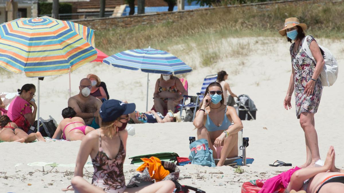 Un grupo de jóvenes con mascarilla en una playa.