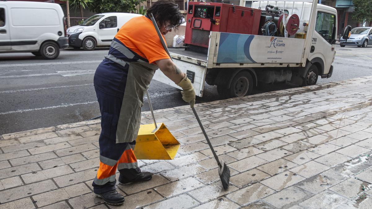 Una operaria de la UTE retirando chicles pegados en la acera en Alicante