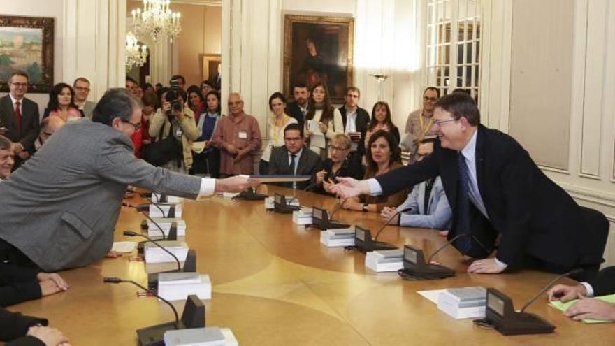 El presidente de la Generalitat recibe el informe elaborado por el comité de expertos universitarios, ayer en las Corts.