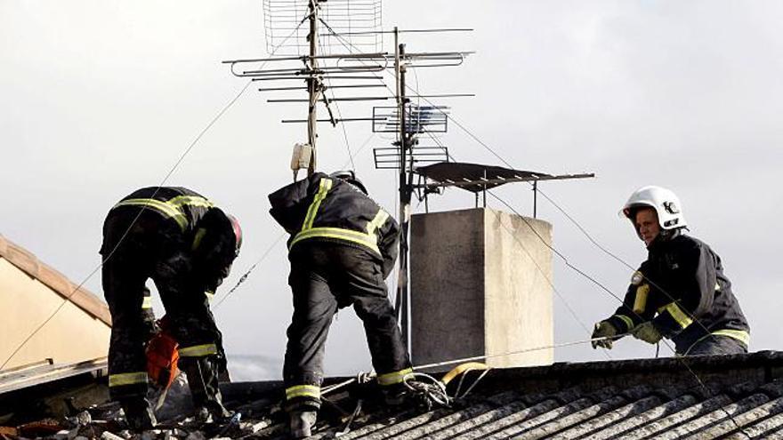 Varios bomberos intentan acceder por el tejado a una vivienda en la localidad navarra de Etxarri Aranatz, donde esta mañana se ha producido un incendio en el que ha fallecido una anciana de 90 años.