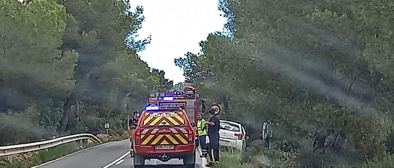 Los bomberos junto al coche incendiado ayer en la carretera de Cala Llonga.