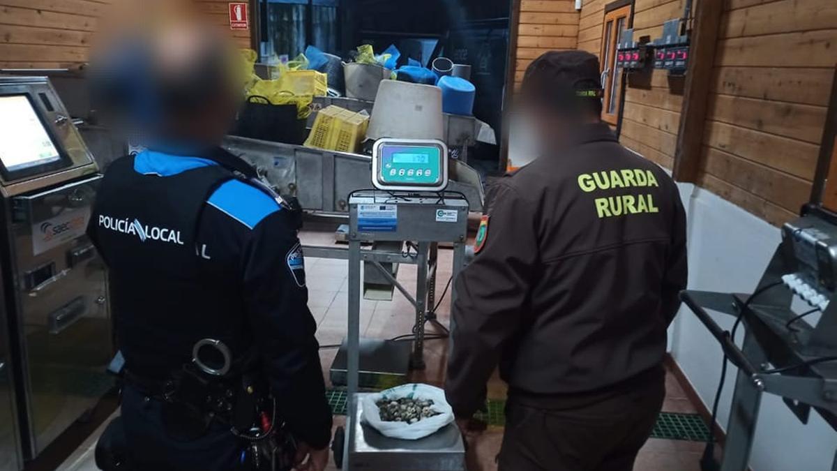 Agentes de la policía local y guardiapescas con la almeja intervenida.