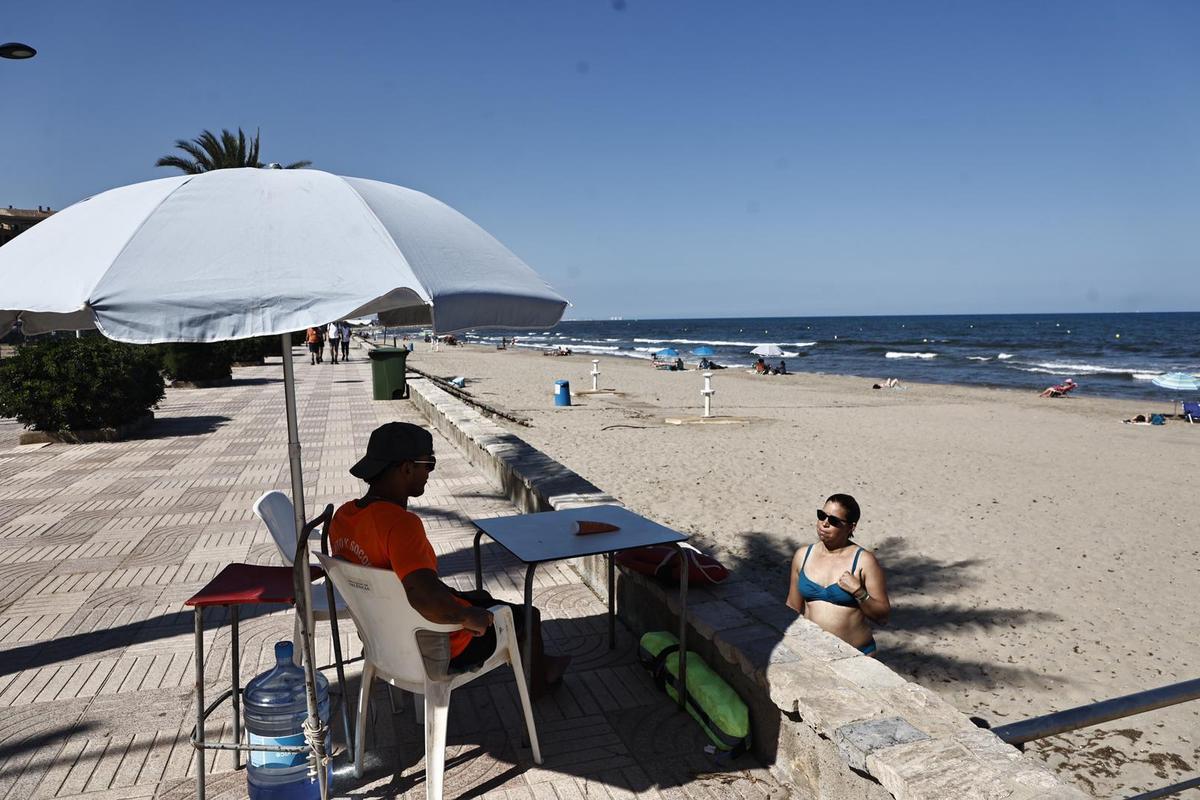 Un socorrista del puesto de la playa norte de Port Saplaya charla con una bañista.