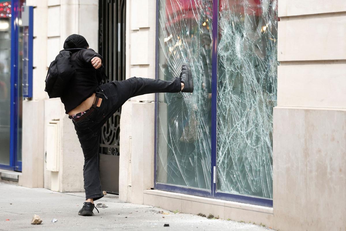 Un manifestante destruye la ventana de un banco durante los enfrentamientos en una manifestación en París como parte del día de huelga general.