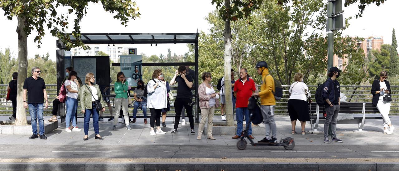 Personas esperando en una parada del autobús urbano de Zaragoza en una de las horas de paro.