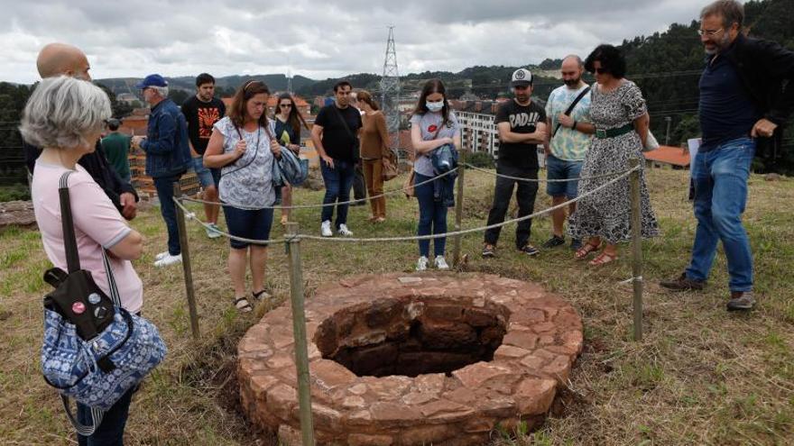 Un grupo de visitantes mira uno de los aljibes hallados en el transcurso de las campañas arqueológicas en el castillo de Gauzón.