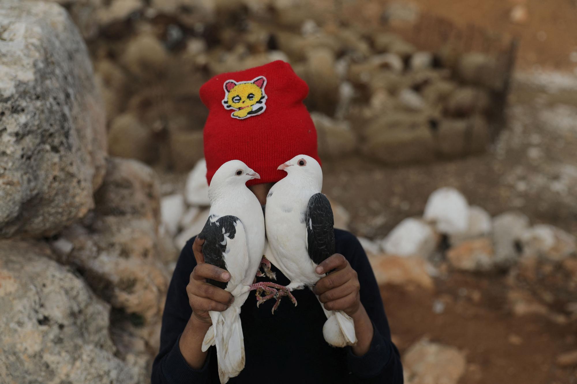 Khalid Abu Khalifa, de 9 años, sujeta dos palomas mientras juega en las ruinas de Babisqa, Siria.