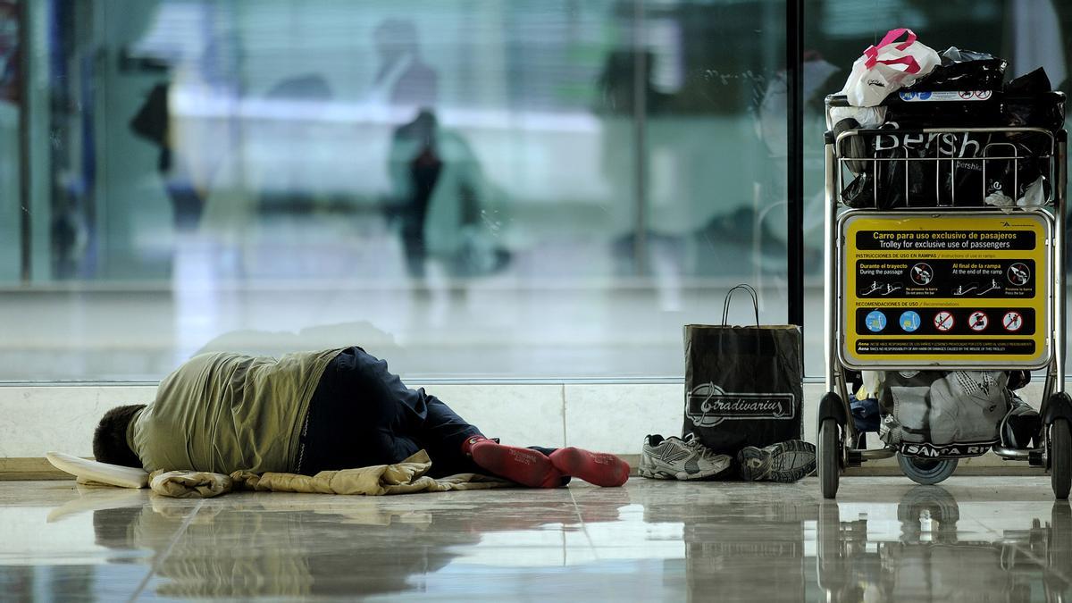 Una persona duerme en la terminal 4 del aeropuerto Madrid-Barajas. José Luis Roca/ Video Atlas