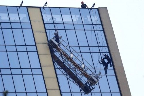 Limpiadores de ventanas cuelgan varados en la fachada de un hotel en el centro de Santiago, 26 de noviembre de 2014. Los bomberos rescataron a dos limpiadores de ventanas atrapados en un andamio que colgaba a una altura de 50 metros, no se registraro