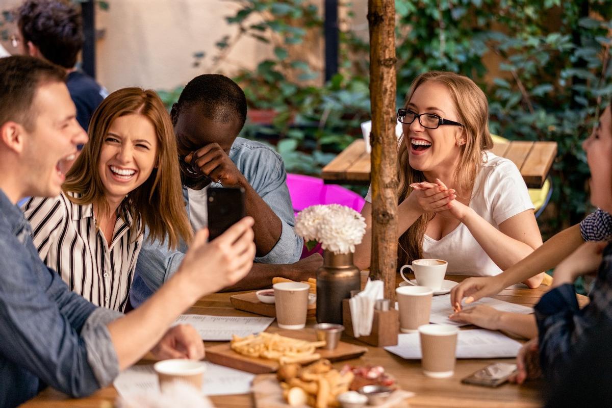 Varios compañeros se parten de risa durante una comida de empresa