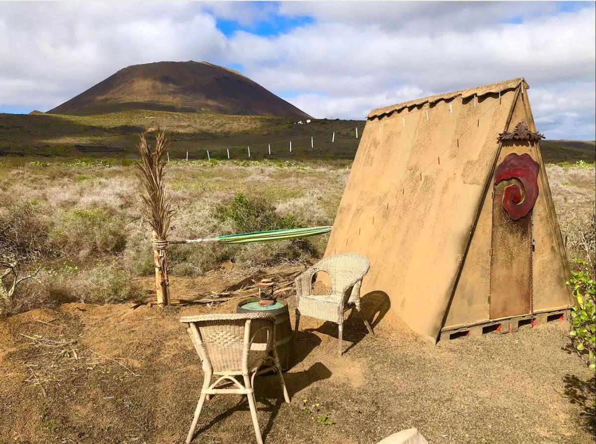 Exterior de la choza que se anuncia como alojamiento ecológico en el norte de Lanzarote. Al fondo, el volcán de La Corona.