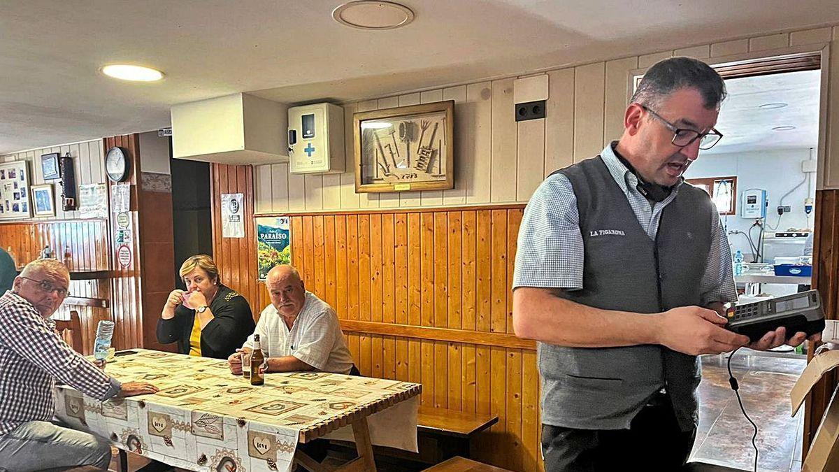 En primer término, José Antonio Benítez, en el bar La Figarona, con el datáfono, y unos clientes al fondo.