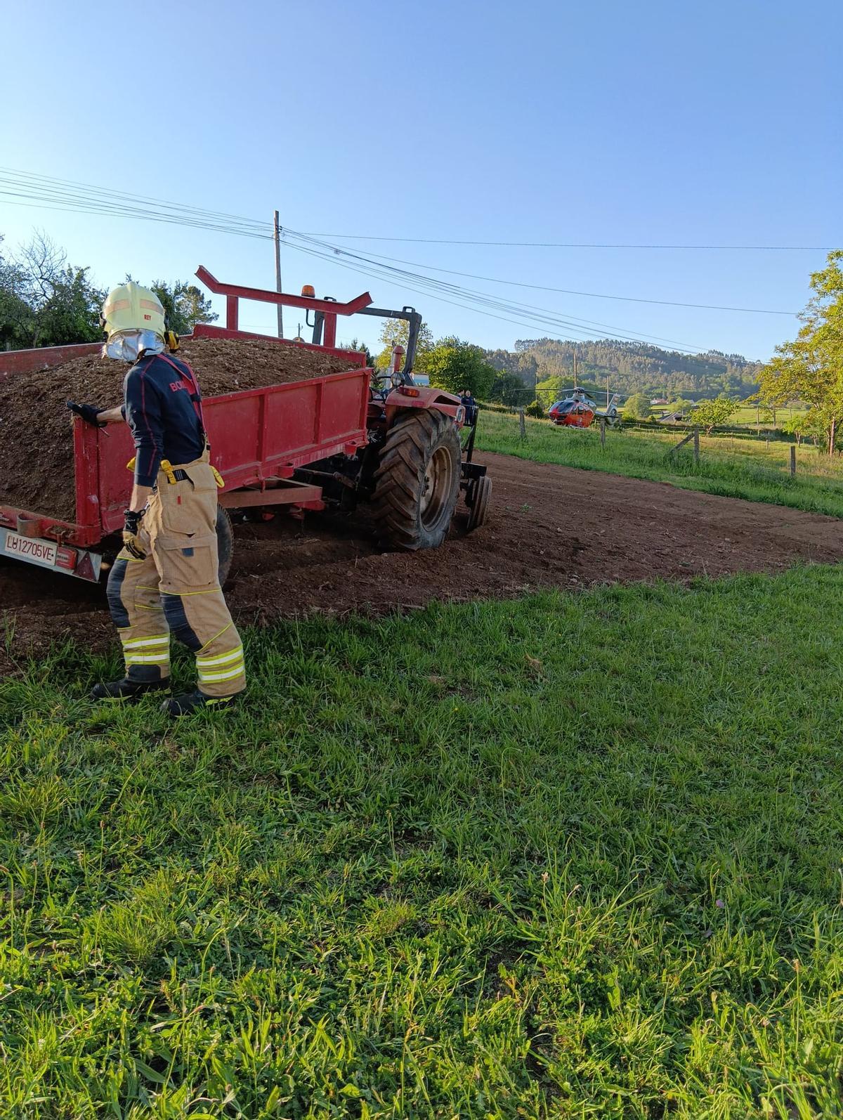Un bombero junto al tractor del que cayó el vecino herido